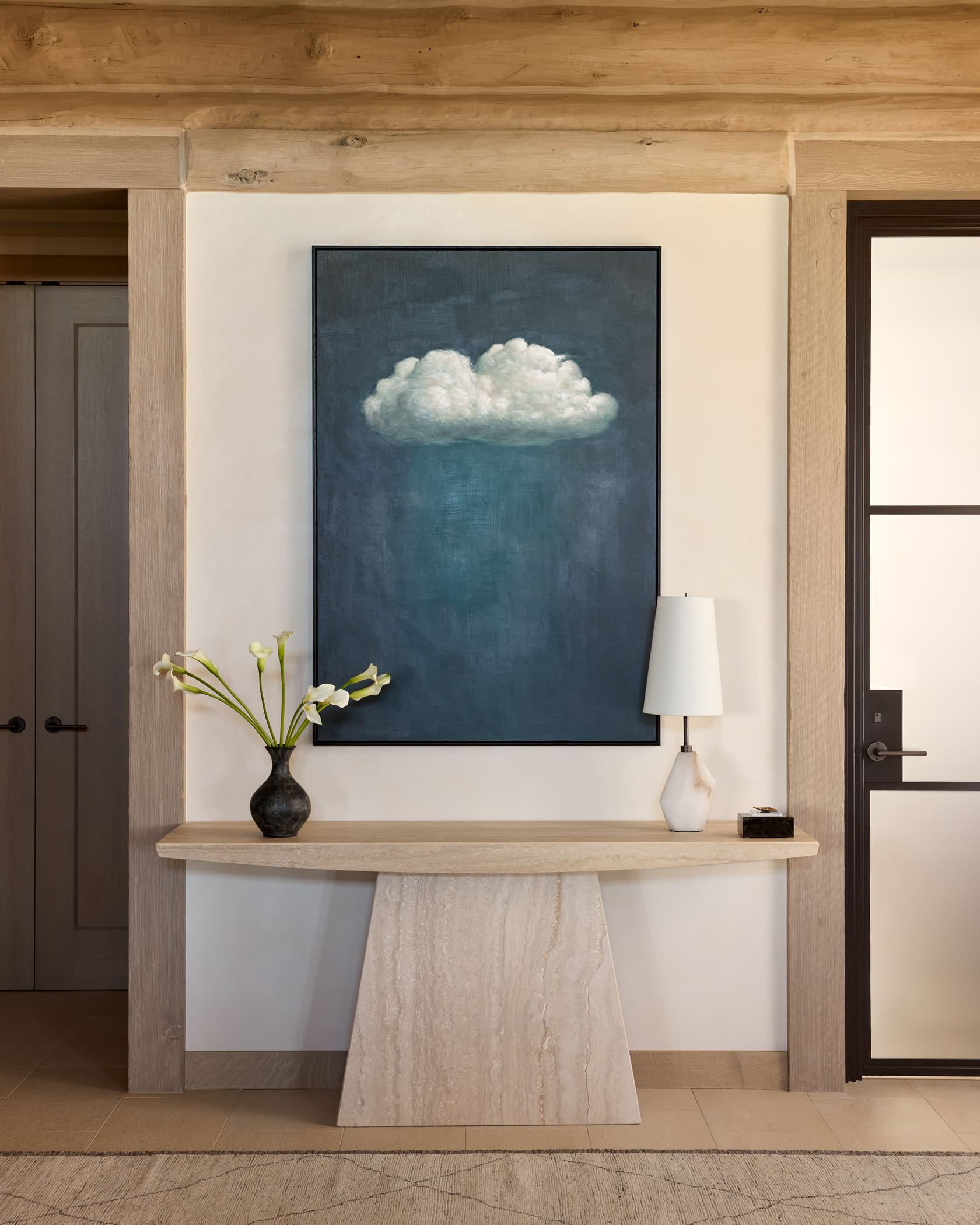 Entry with travertine console, cloud painting, and bleached log beam framing, Snowmass log cabin remodel by Rowland+Broughton