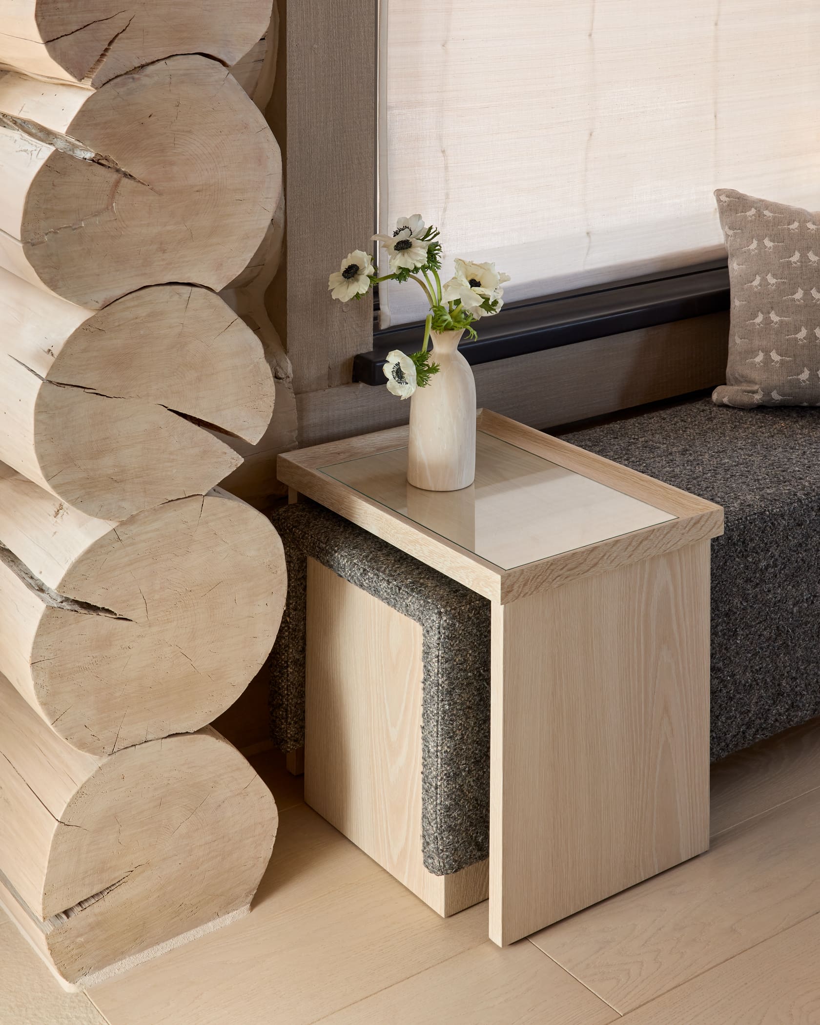 Bleached log wall detail with oak side table, glass top, and anemone flowers, Snowmass log cabin remodel