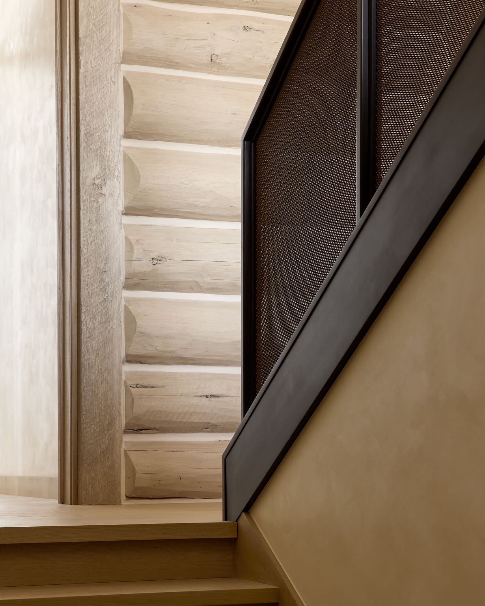 Staircase detail with custom perforated metal guardrail, blackened steel frame, and bleached log wall, Snowmass cabin remodel