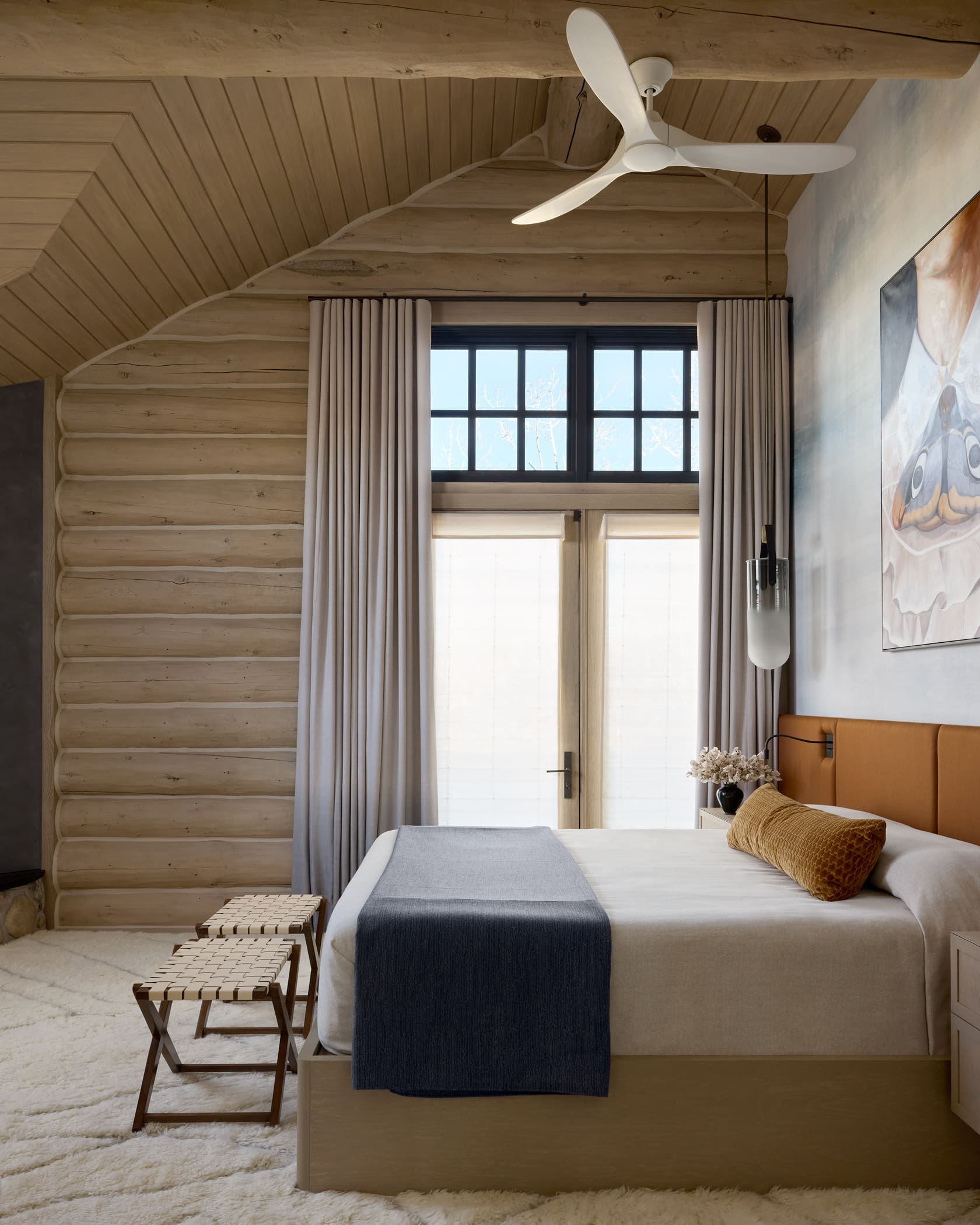 Primary suite with bleached log walls, leather headboard, linen drapes, and woven bench, Snowmass log cabin remode